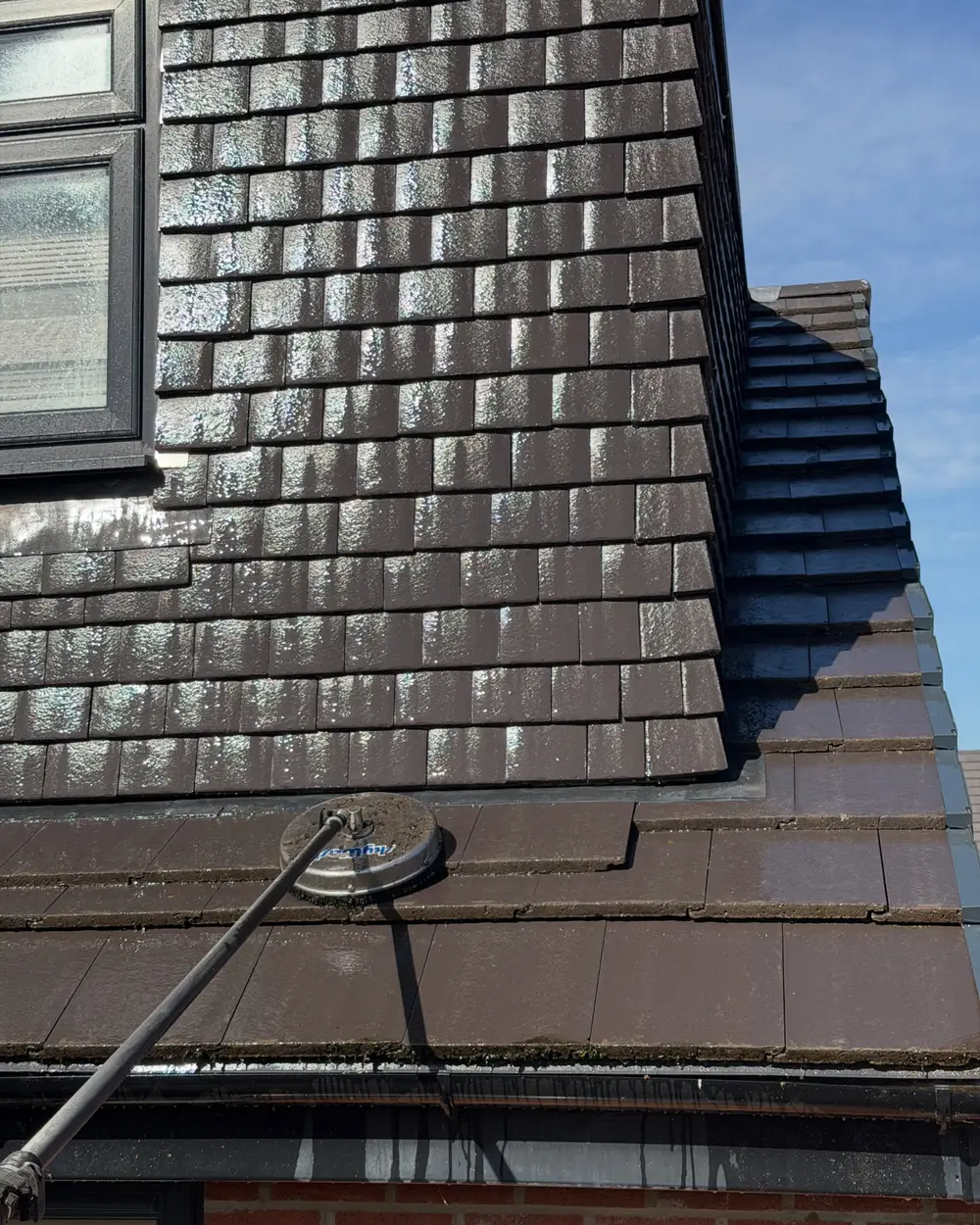 Telescopic cleaning pole working along a tiled roof edge above the gutter line